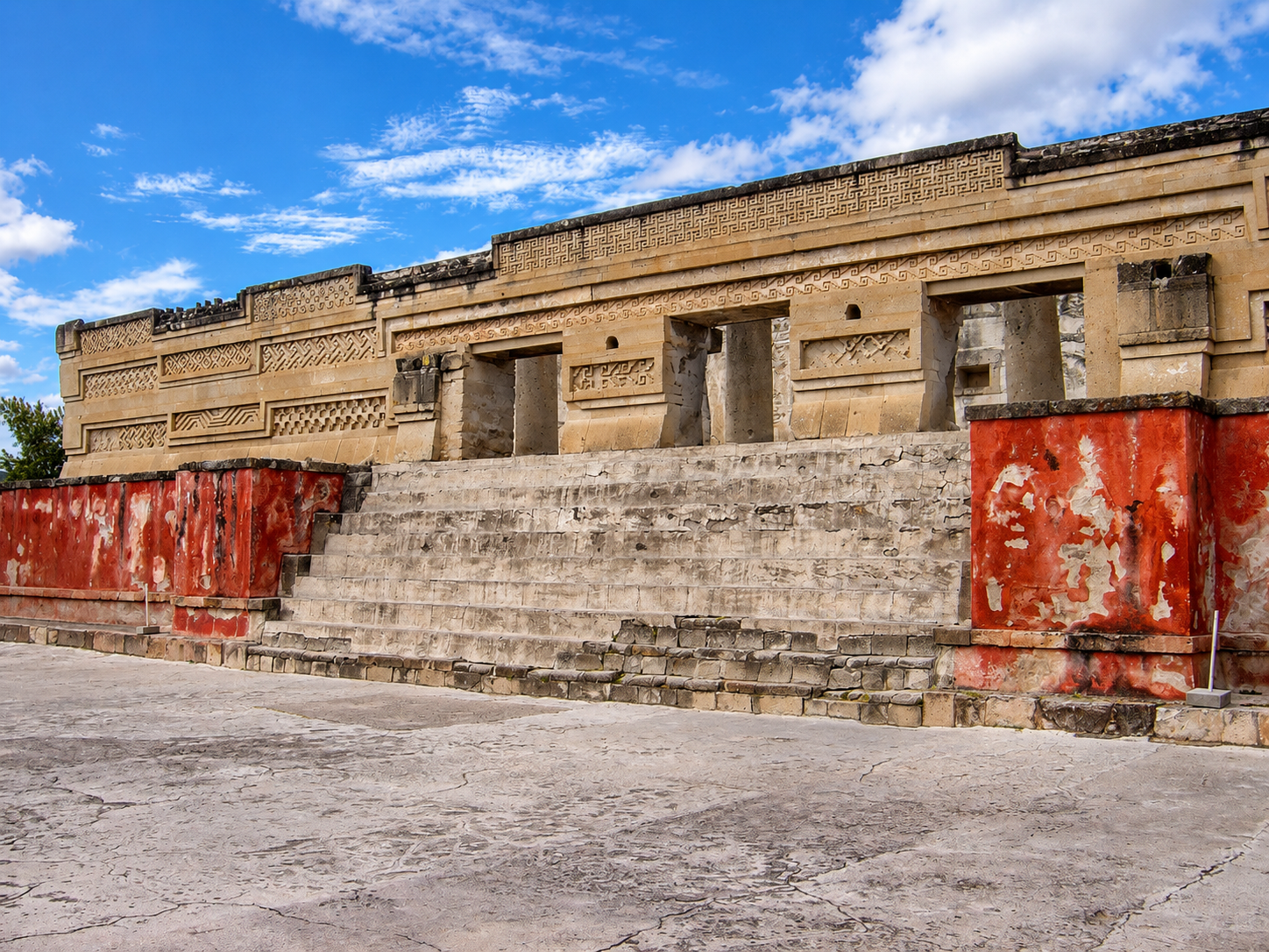 The ancient stone ruins of Mitla with intricate Zapotec geometric carvings and red walls under a bright blue sky