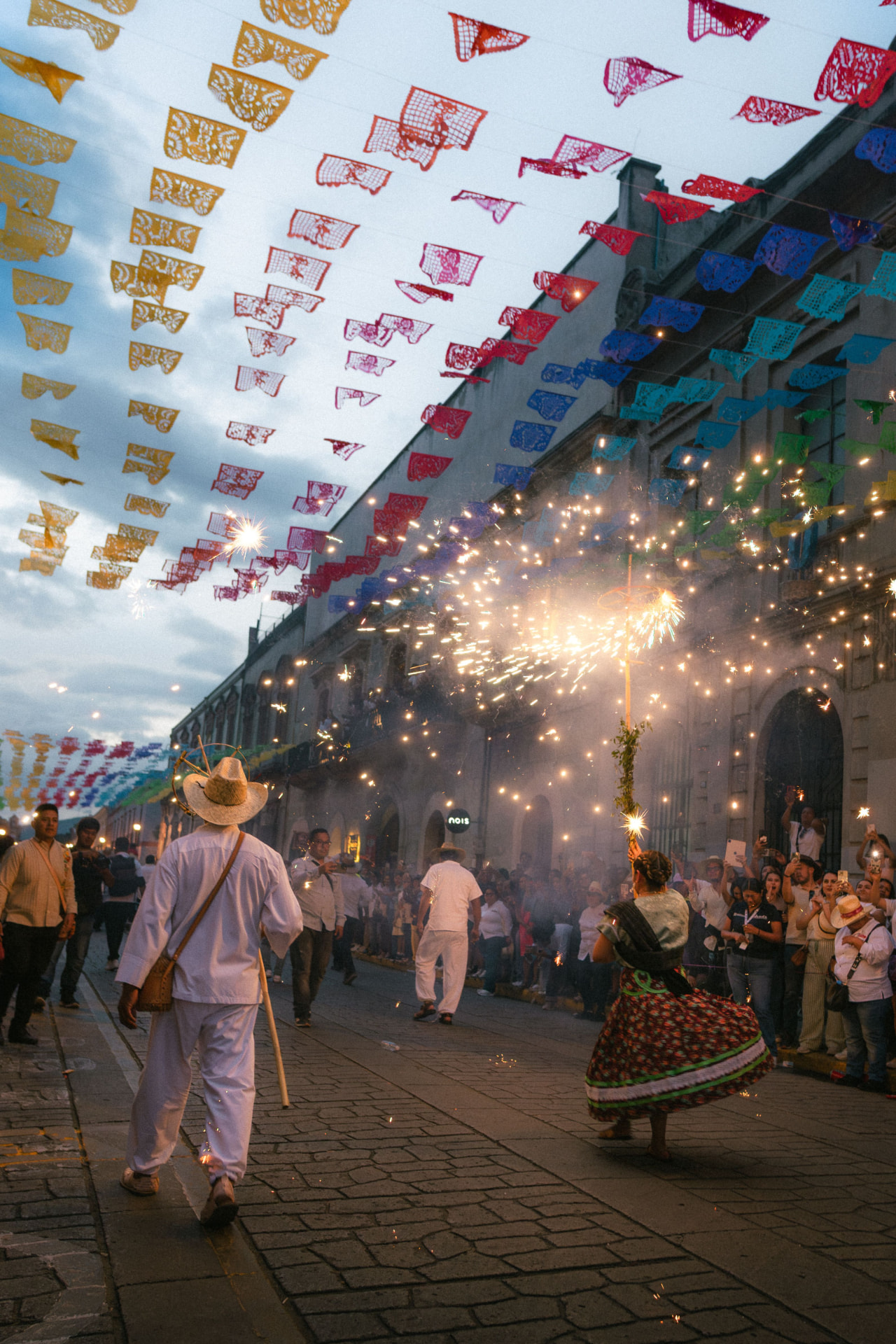 A vibrant Oaxaca street celebration with papel picado banners and traditional dancers